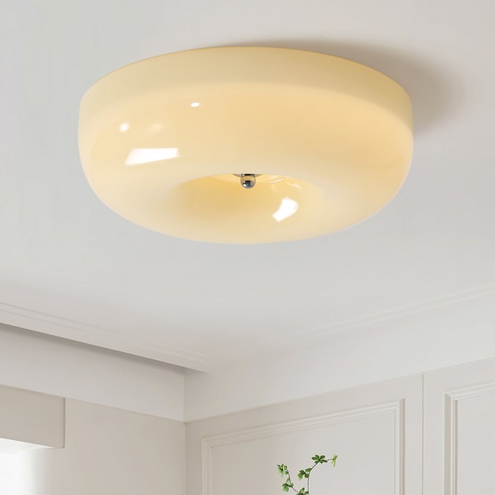 Detailopname van de ronde crèmekleurige glazen plafondlamp in de ruimte.