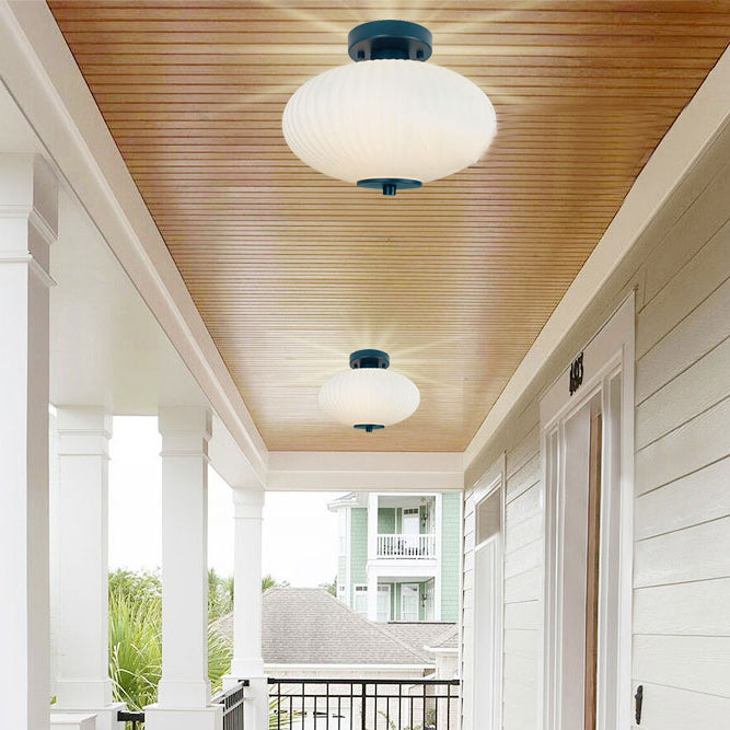 Een overdekte veranda met een ovale glazen plafondlamp.