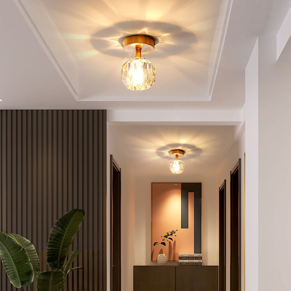 Hal en woonkamer met twee ingebouwde plafondlampen van goudkleurig glas.