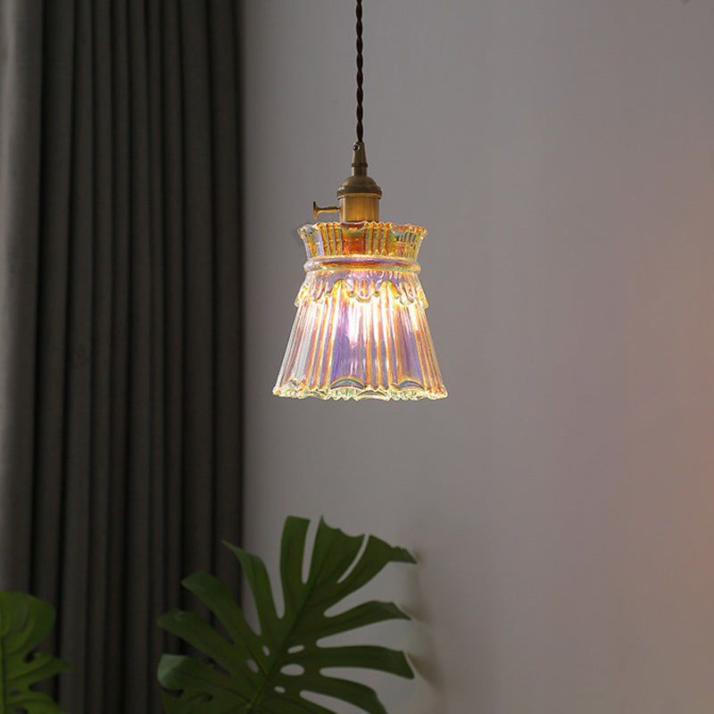 Enkele hanglamp met transparante glazen kap, vlakbij de gordijnen.