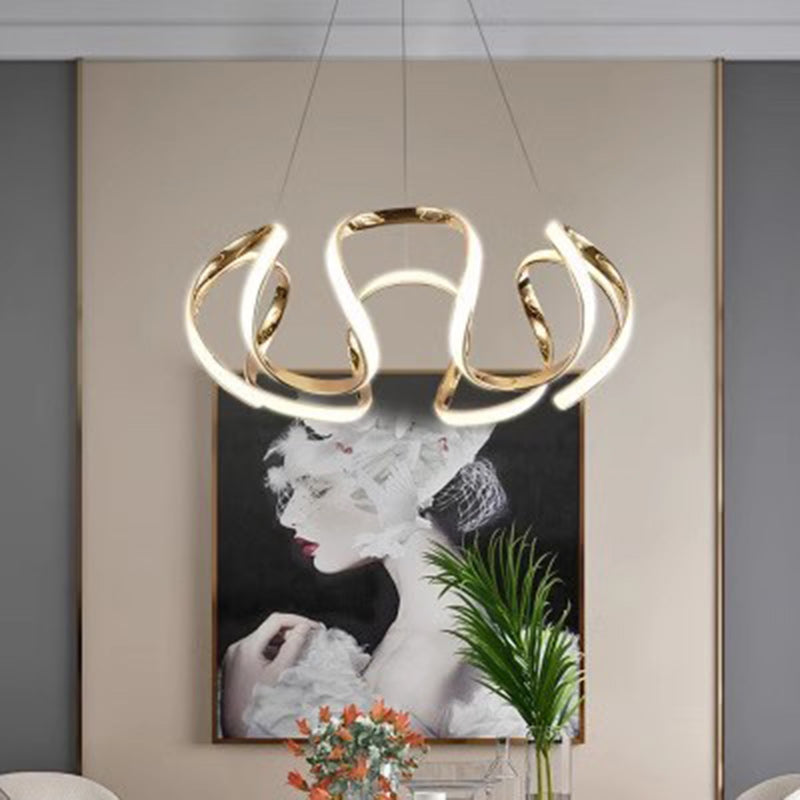 Lampadario dorato installato in una stanza con parete decorata con opere d'arte e piante.