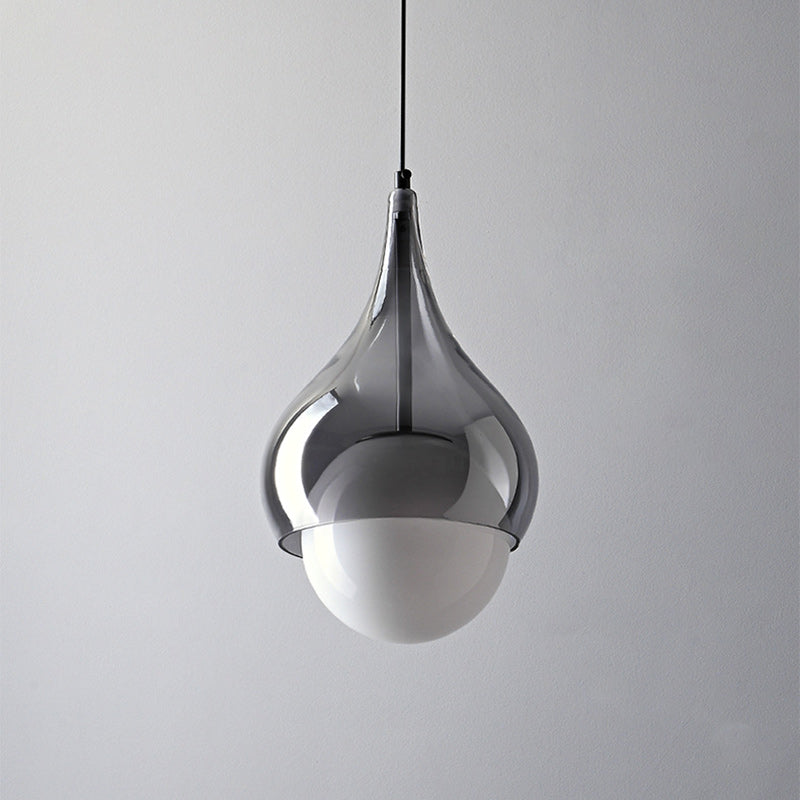 Close-up van een rookgrijze glazen hanglamp met koperen details, zonder verlichting.