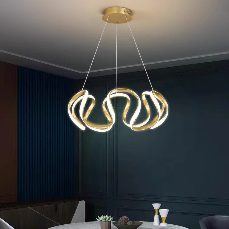 Lampadario dorato in sala da pranzo con parete scura sullo sfondo.