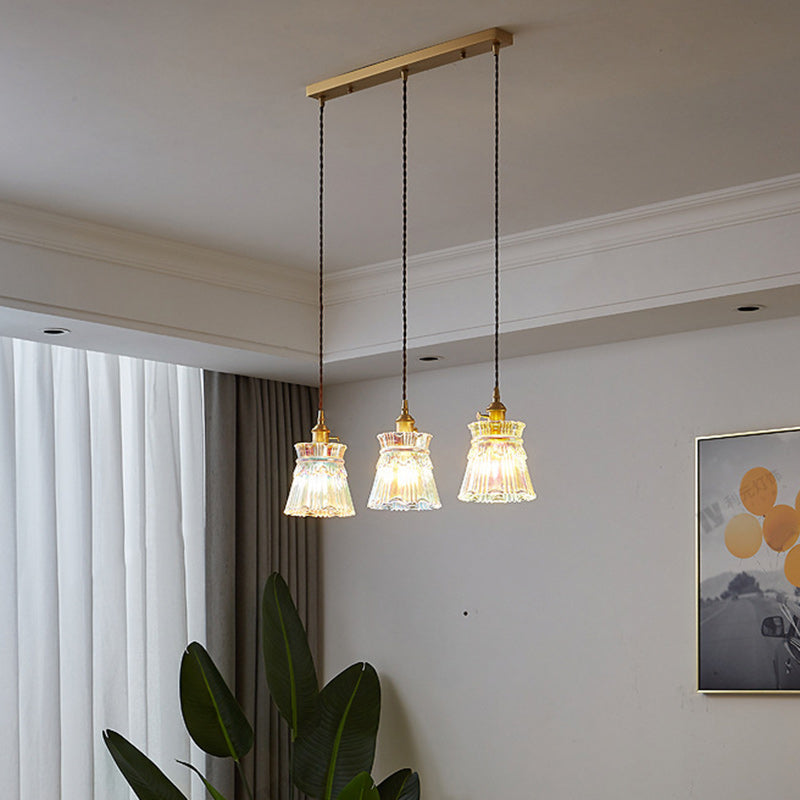 Hanglamp met drie lampen en lineaire voet in een kameromgeving.