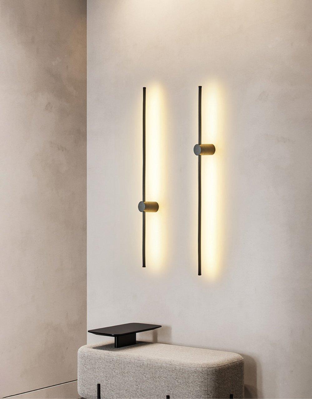 Deux luminaires linéaires verticaux éclairés sur un mur intérieur