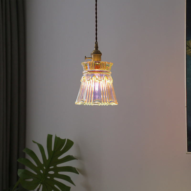 Enkele transparante glazen koperen hanglamp in een kameromgeving.
