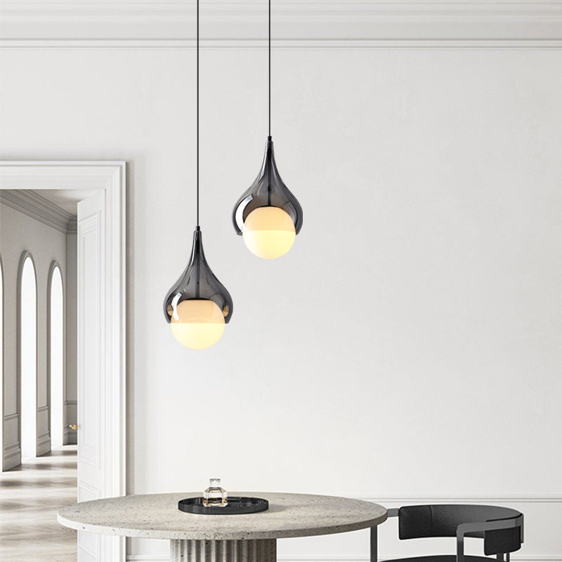 Twee hanglampen van rookgrijs glas in een lichte eet- en woonkamer.