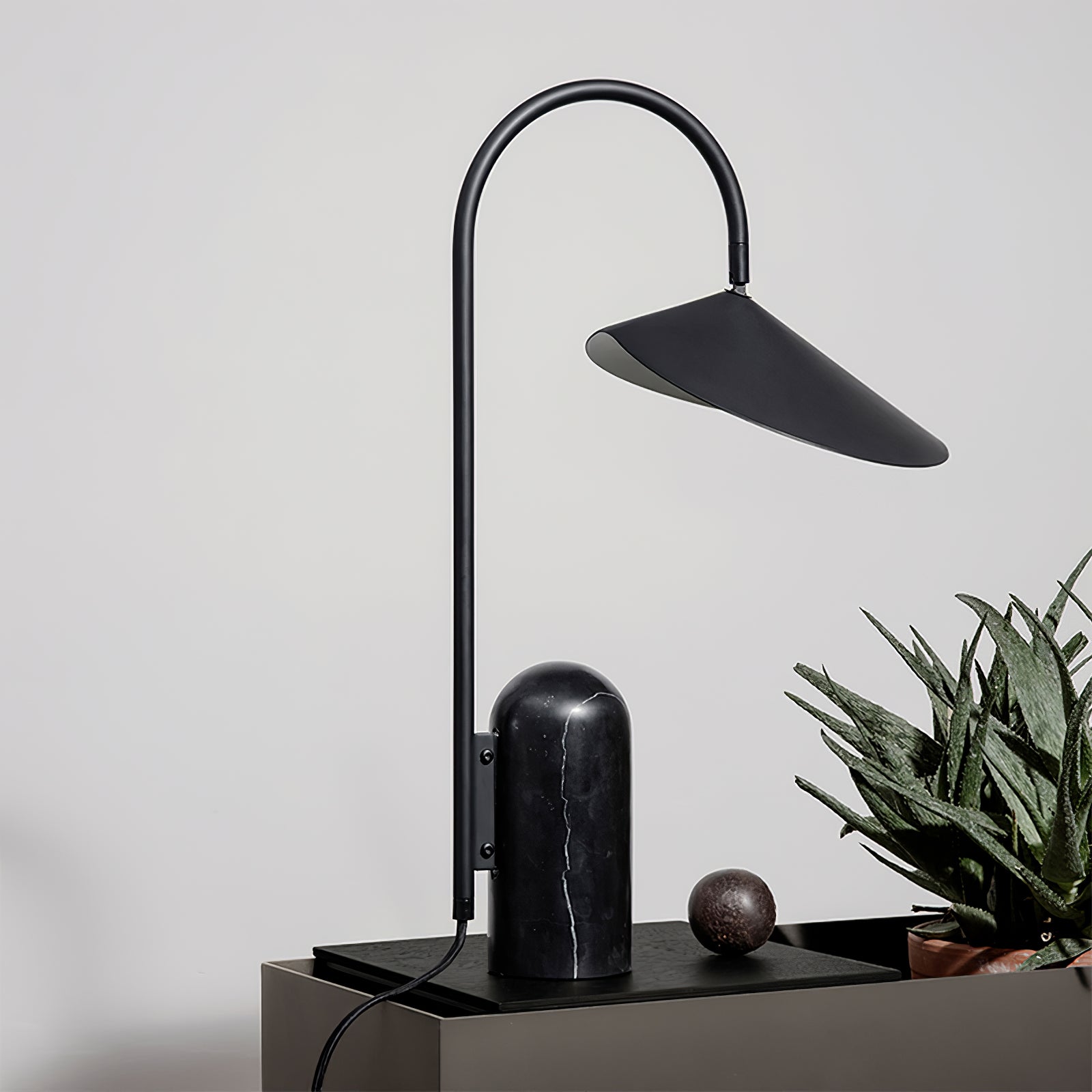 Schwarze Lampe auf dunklem Tisch mit Pflanze