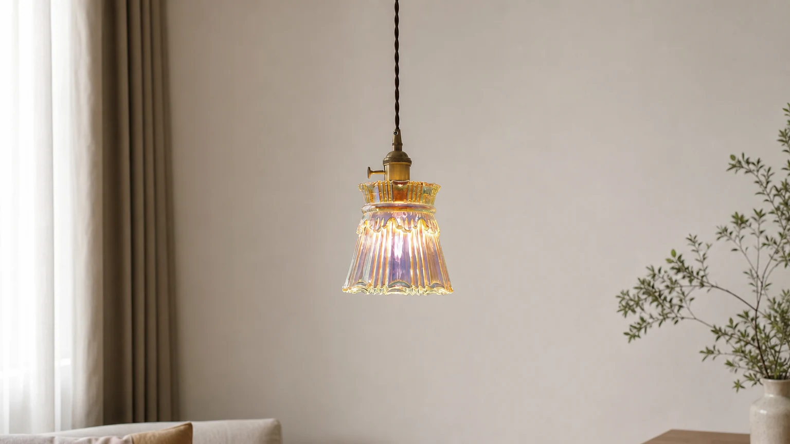 Transparante glazen hanglamp met koperen accenten in een sfeervolle woonkamer.