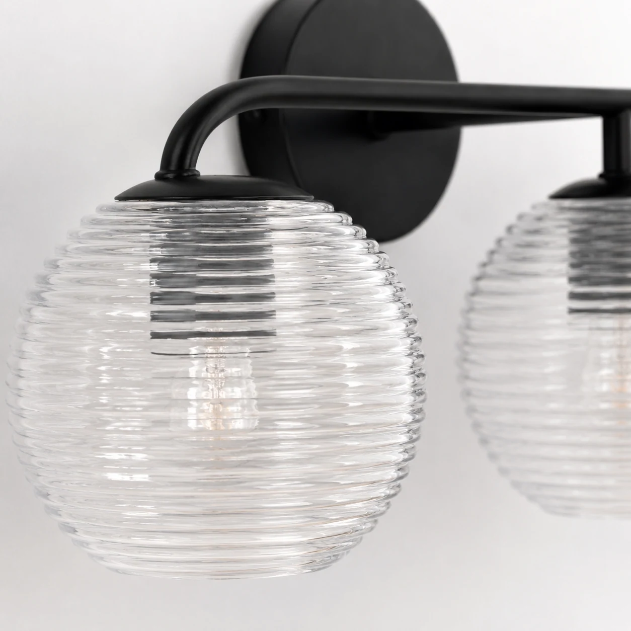 Detailaufnahme des gerippten Glasschirms und des schwarzen Metallrahmens der Huxley-Lampe.